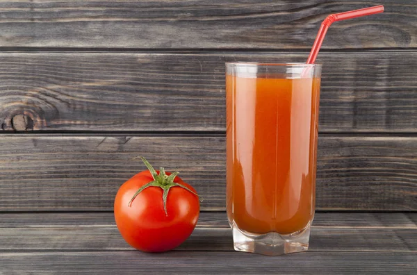 Pomodori succosi e succo su uno sfondo di legno — Foto Stock