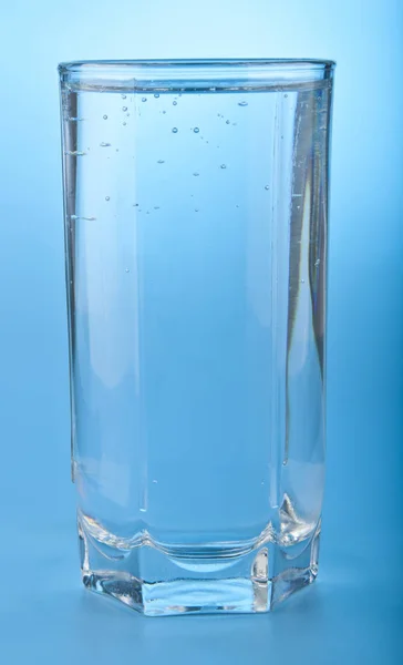 Glas mit Wasser auf blauem Hintergrund — Stockfoto