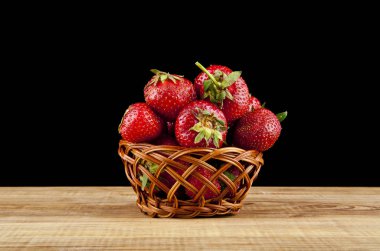 siyah bir zemin üzerine bir sepet içinde çilek