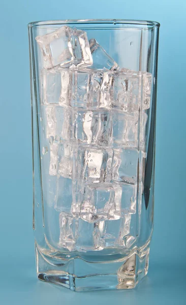 Glas med vatten och is på en blå bakgrund — Stockfoto