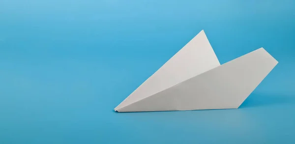 Wit papieren vliegtuig op een blauwe achtergrond — Stockfoto