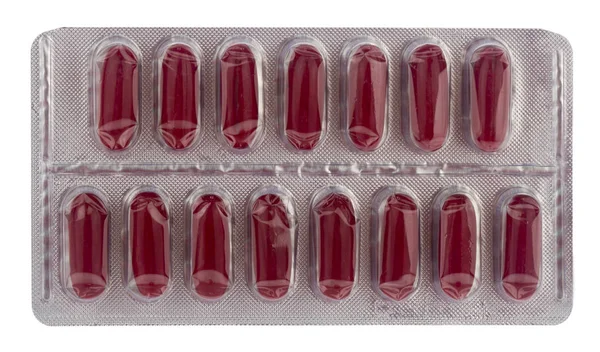 Pílulas vermelhas em embalagens de prata isoladas em um fundo branco . — Fotografia de Stock