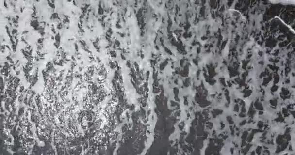 Top down aerial view of waves on black sand beach — 비디오