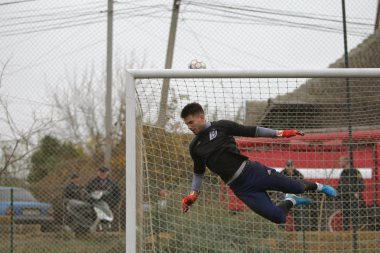 Odessa, Ukrayna - 2019 yılı: Yerel bir futbol takımının kalecisi, kötü bir futbol sahasında bölgesel bir derbi şampiyonasında oynarken kurtarıyor. Futbol golü, gol kalesi