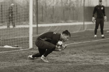 Odessa, Ukrayna - 2019 yılı: Yerel bir futbol takımının kalecisi, kötü bir futbol sahasında bölgesel bir derbi şampiyonasında oynarken kurtarıyor. Futbol golü, gol kalesi