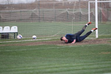 Odessa, Ukrayna - 2019 yılı: Yerel bir futbol takımının kalecisi, kötü bir futbol sahasında bölgesel bir derbi şampiyonasında oynarken kurtarıyor. Futbol golü, gol kalesi