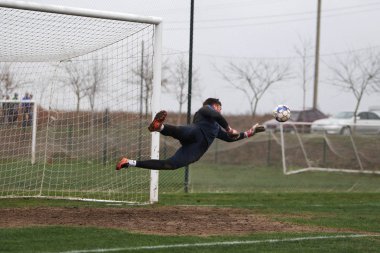 Odessa, Ukrayna - 2019 yılı: Yerel bir futbol takımının kalecisi, kötü bir futbol sahasında bölgesel bir derbi şampiyonasında oynarken kurtarıyor. Futbol golü, gol kalesi