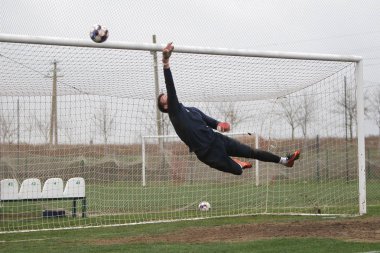 Odessa, Ukrayna - 2019 yılı: Yerel bir futbol takımının kalecisi, kötü bir futbol sahasında bölgesel bir derbi şampiyonasında oynarken kurtarıyor. Futbol golü, gol kalesi