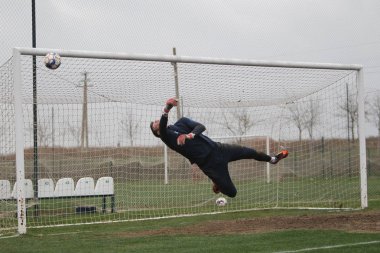 Odessa, Ukrayna - 2019 yılı: Yerel bir futbol takımının kalecisi, kötü bir futbol sahasında bölgesel bir derbi şampiyonasında oynarken kurtarıyor. Futbol golü, gol kalesi