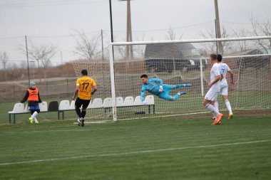 Odessa, Ukrayna - 2019 yılı: Yerel bir futbol takımının kalecisi, kötü bir futbol sahasında bölgesel bir derbi şampiyonasında oynarken kurtarıyor. Futbol golü, gol kalesi