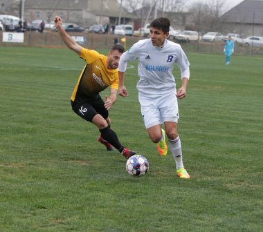 Odessa, Ukrayna-Circa 2019: Kötü bir futbol sahasında bölgesel Derby şampiyonasında yerel futbol takımının futbolcuları. Stadyumun çimen yeşili sahasında sıcak bir futbol maçı var.