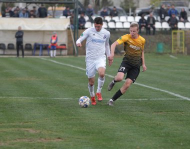Odessa, Ukrayna-Circa 2019: Kötü bir futbol sahasında bölgesel Derby şampiyonasında yerel futbol takımının futbolcuları. Stadyumun çimen yeşili sahasında sıcak bir futbol maçı var.