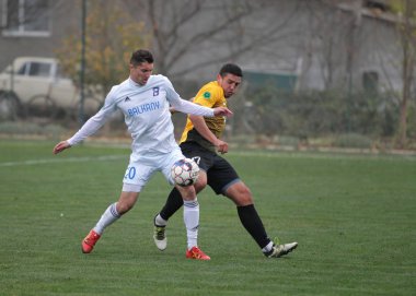 Odessa, Ukrayna-Circa 2019: Kötü bir futbol sahasında bölgesel Derby şampiyonasında yerel futbol takımının futbolcuları. Stadyumun çimen yeşili sahasında sıcak bir futbol maçı var.