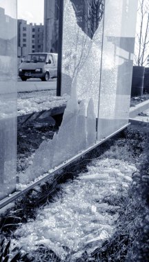 Otobanda kırık cam otobüs durağı. Vandallar camı kırdı. Küçük parçalar ve sertleştirilmiş cam çatlakları. Holiganlık, vandalizm ve suç geçmişi