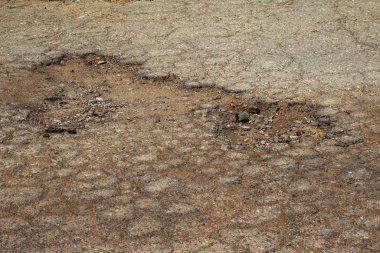 Çukurlu asfalt yolda hasar var. Kötü yol. Bozuk asfalt, bozuk otomobil yolu, çatlaklar, delikler, asfalttaki çukurlar.