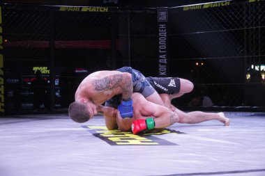 Odessa, Ukrayna-30 Haziran 2019: Mma boksörlerinin dövüşçüleri sekizgen kafes ringinde kuralsız dövüşüyorlar. Mma dövüşçüleri şampiyonada ringde