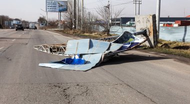 ODESSA, UKRAINE - February 24, 2020: billboard on street is demolished by strong wind on stormy day during hurricane. Strong gusty hurricane wind turned billboard onto car road