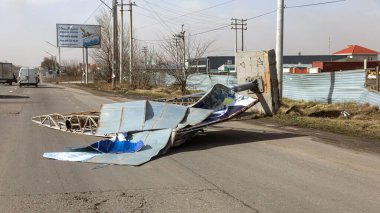 ODESSA, UKRAINE - February 24, 2020: billboard on street is demolished by strong wind on stormy day during hurricane. Strong gusty hurricane wind turned billboard onto car road