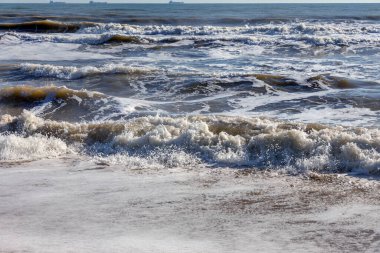 Yumuşak bir deniz dalgası kumsalda yuvarlanıyor. Sahilde deniz manzarası dalgaları