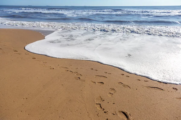 A soft sea wave rolls onto the sand of the beach. Seascape waves on the coast