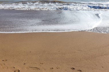 Yumuşak bir deniz dalgası kumsalda yuvarlanıyor. Sahilde deniz manzarası dalgaları