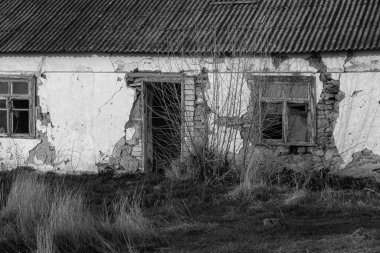 Pencereleri ve duvarları harap olmuş terk edilmiş eski bir bina. Eski tuğla duvarda kocaman çatlaklar var. Terk edilmiş eve gerek yok. Deprem üstüne yıkım. Kıyamet