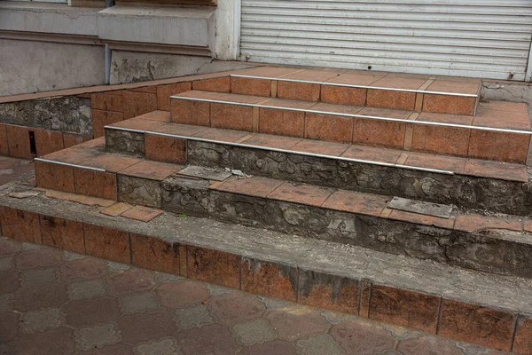 An old open outer stone staircase. Stone, cement steps of the old staircase with traces of weathering and destruction. An ancient stone staircase, ancient broken worn steps. Selective focus