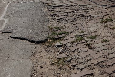 Çukur çukurları olan hasarlı bir yol, kış aylarında buzların çözülmesinden kaynaklanıyor. Kötü yol. Kaldırımda kırık kaldırımlar var. Kaldırım kaldırımları kusurlu ve çatlak perspektiften geliyor.