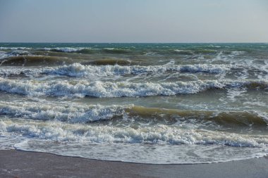Bir deniz dalgası sahildeki bir kumsalda köpükle koşuyor. Günbatımı renklerinde deniz manzarası. Tasarım ve dekorasyon için güzel doğal arkaplan