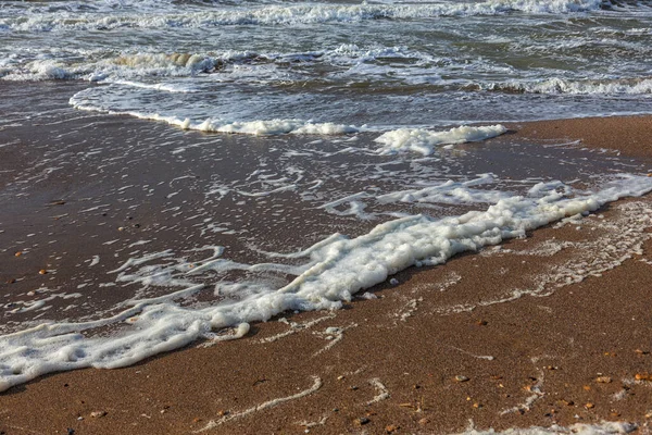 海岸に泡のビーチの砂の上に海の波が走ります 夕日の色の海 デザインと装飾のための美しい自然の背景 — ストック写真