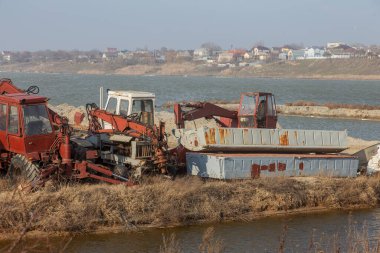 Kimsenin ihtiyacı olmayan eski paslı mühendislik ekipmanları, eski traktör, vinç, paslı kazıcı suya yakın bir atık sahasına terk edilmiş.