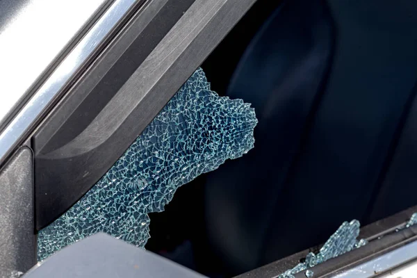 Criminal incident. Hacking a car. Broken driver's side window of car. Thieves smashed window of car with fragments inside, glass was scattered throughout. Crime - broken window and theft belongings