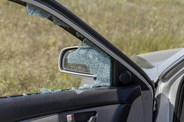 Criminal incident. Hacking a car. Broken driver\'s side window of car. Thieves smashed window of car with fragments inside, glass was scattered throughout. Crime - broken window and theft belongings