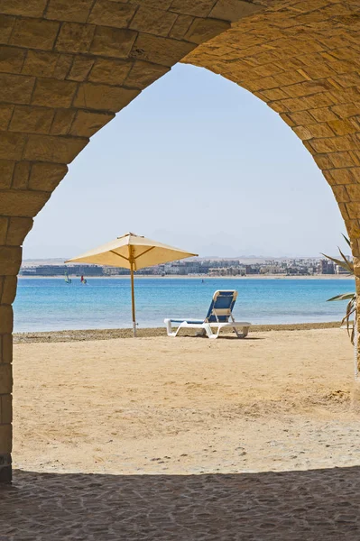 Sunbed on a tropical beach through archway — Stock Photo, Image