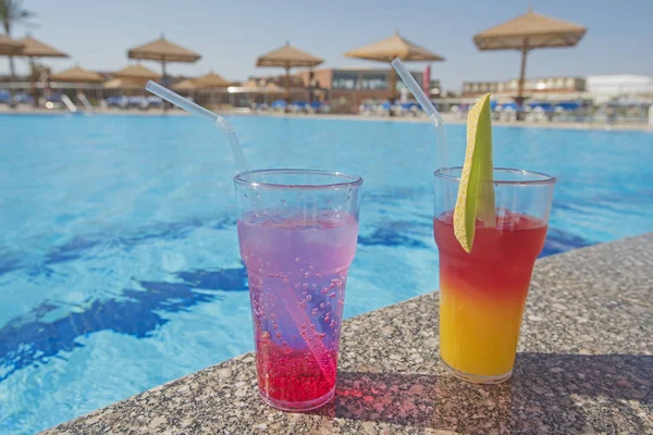 Dos copas de cóctel junto a una piscina tropical —  Fotos de Stock