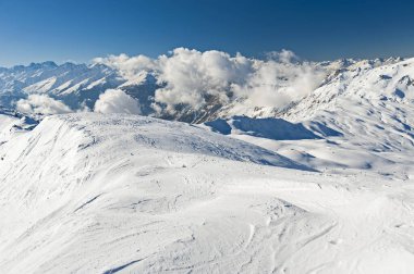 Panoramik manzara aşağı kar kaplı vadi Alp dağlarında mavi gökyüzü arka planında bulutlarla kaplı.