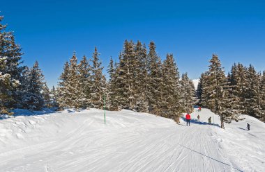 Panoramik manzara vadisi manzarası. Kayakçılar kış Alp Dağları 'nda kayak pistinden aşağı iniyor.