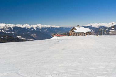 Yokuştaki uzak kafe binalı, karla kaplı alp kayak merkezinin panoramik manzarası