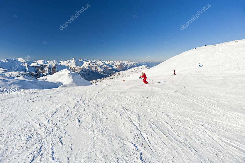 Panoramic landscape valley view down a ski slope piste in winter alpine mountain resort
