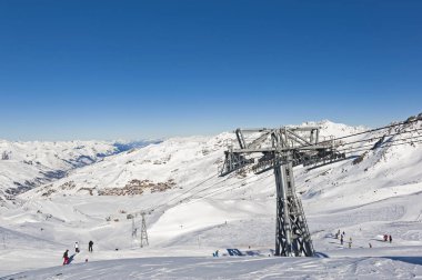 Alp Dağları 'ndaki kayak merkezindeki karla kaplı panoramik manzara mavi gökyüzü arka planında iskemle kaldırma ile