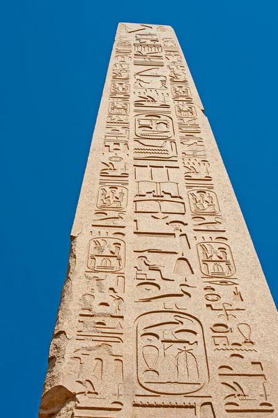 在卢克索的卡尔纳克神庙 有一个高大的古埃及方尖碑 蓝天背景上有象形文字的雕刻 — 图库照片