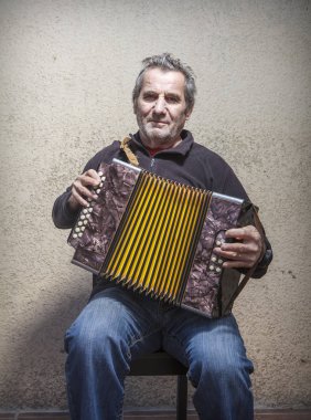 Yaşlı adam sokakta akordeon çalıyor.