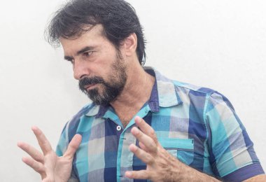 Bir beyazın Siyah sakallı, birkaç gri saç, mavi ekose gömlek giyer, bir şey ilginç, farklı pozisyonlarda ellerini jestlerle bakar.