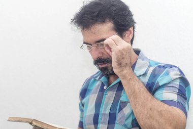 Seyir bir kitap bir mavi ekose gömlek giymiş bir beyazın Siyah sakallı, gri saçlar, gözlük,