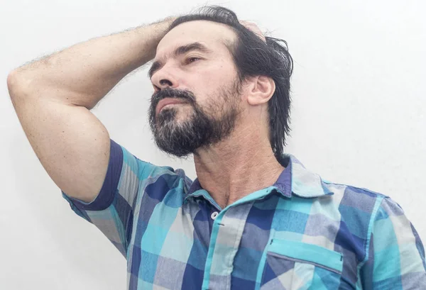 A white man with a black beard, a few gray hairs, wears a blue plaid shirt, looks at something interesting, gestures with his hands in different positions. — Stock Photo, Image