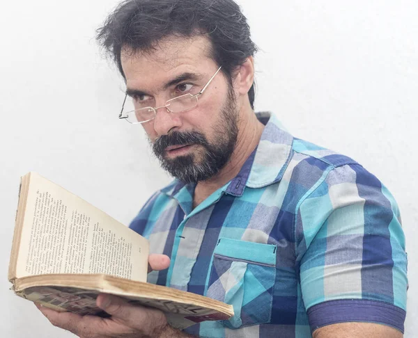 Seyir bir kitap bir mavi ekose gömlek giymiş bir beyazın Siyah sakallı, gri saçlar, gözlük,