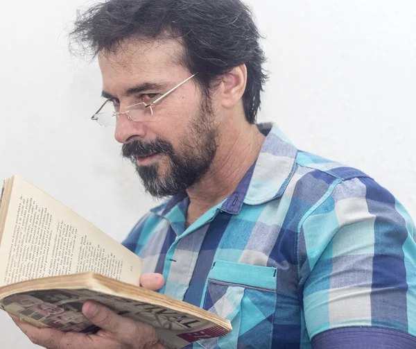 Seyir bir kitap bir mavi ekose gömlek giymiş bir beyazın Siyah sakallı, gri saçlar, gözlük,