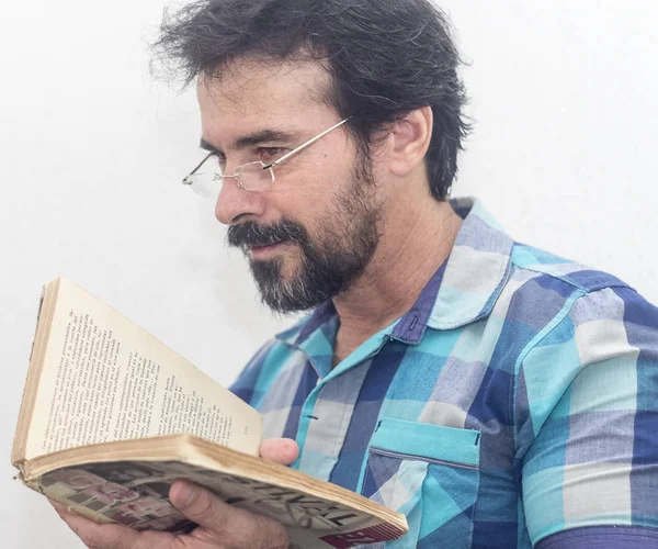 Seyir bir kitap bir mavi ekose gömlek giymiş bir beyazın Siyah sakallı, gri saçlar, gözlük,