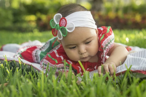 Bebita blanca muy hermosa, sentada en la hierba, con vestido de colores mexicanos, cinta blanca y lazo de colorines en la cabeza. Gesticulando y expresando emociones diversas, originales y muy simpticas, graciosas, sugerentes. Çok doğal sonbahar.