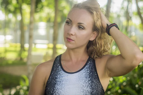 Blond girl, wears sportswear and exercises in the garden